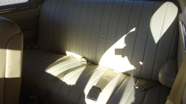 Cream leather backseat of classic car.