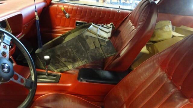 Red interior of a classic car, parts removed.