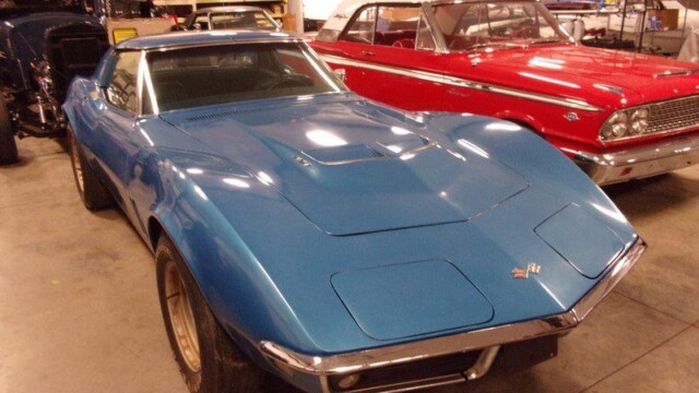 Blue Corvette and red Ford in garage.