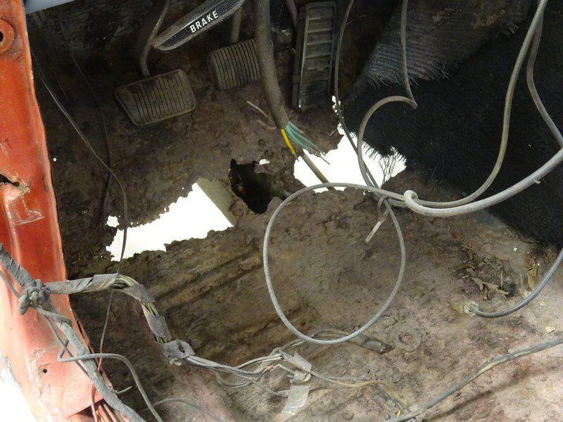 Severely rusted car floor with wires.