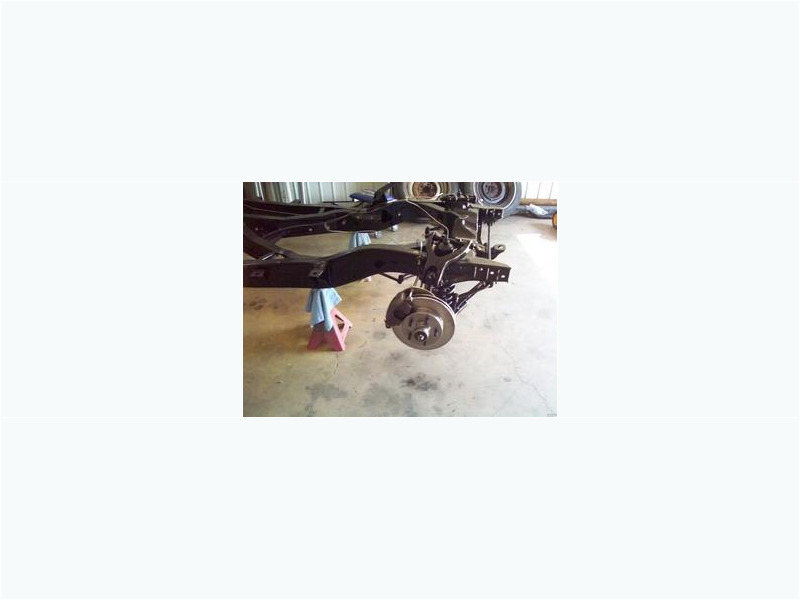 Here's an alt tag for the image: Classic car chassis and front suspension.