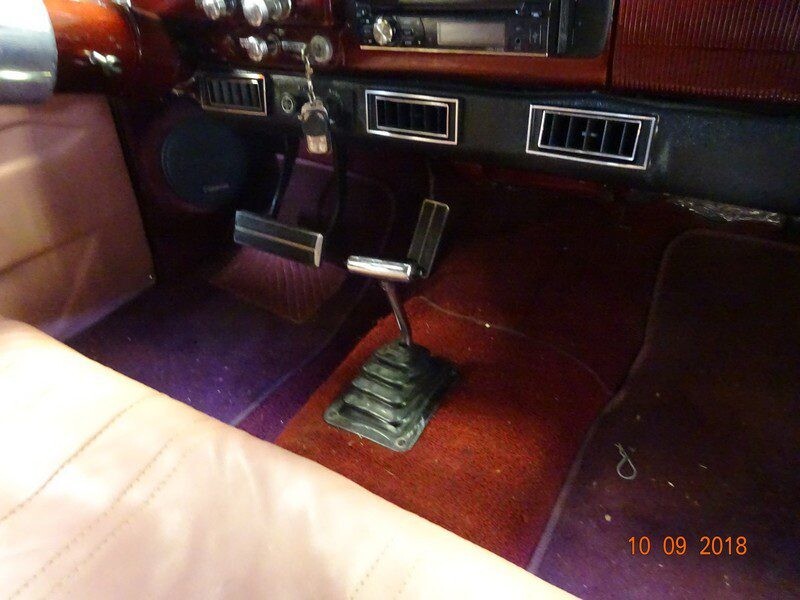 Classic car interior, floor shifter, red carpet.
