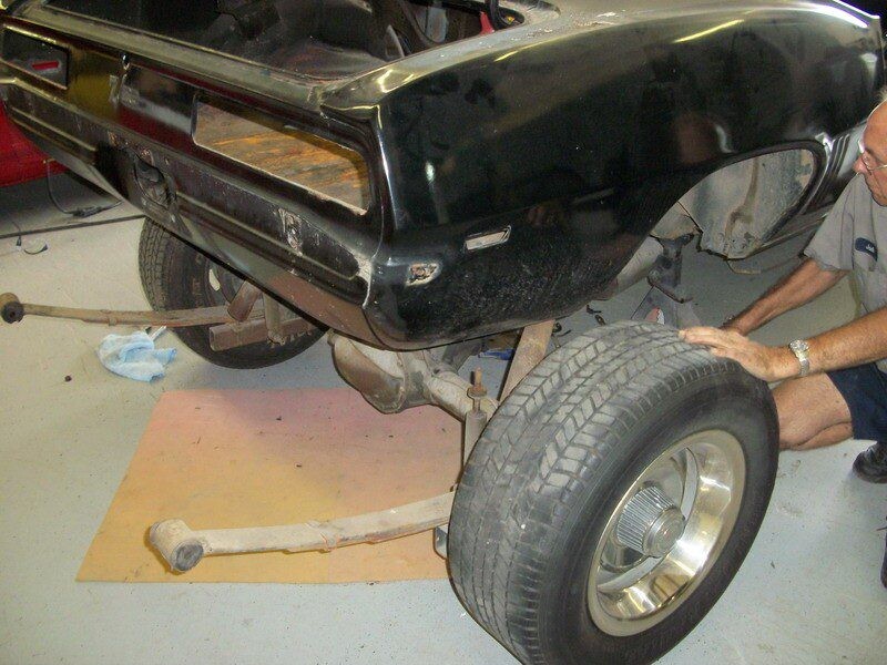 Mechanic repairing classic car's rear suspension.