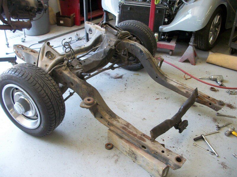 Rusty car chassis frame on floor.
