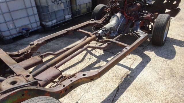 Rusty classic car chassis with engine.