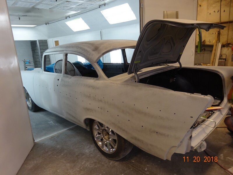 Here's an 8-word alt tag for the image: Primed 1957 Chevy Bel Air in auto body shop.