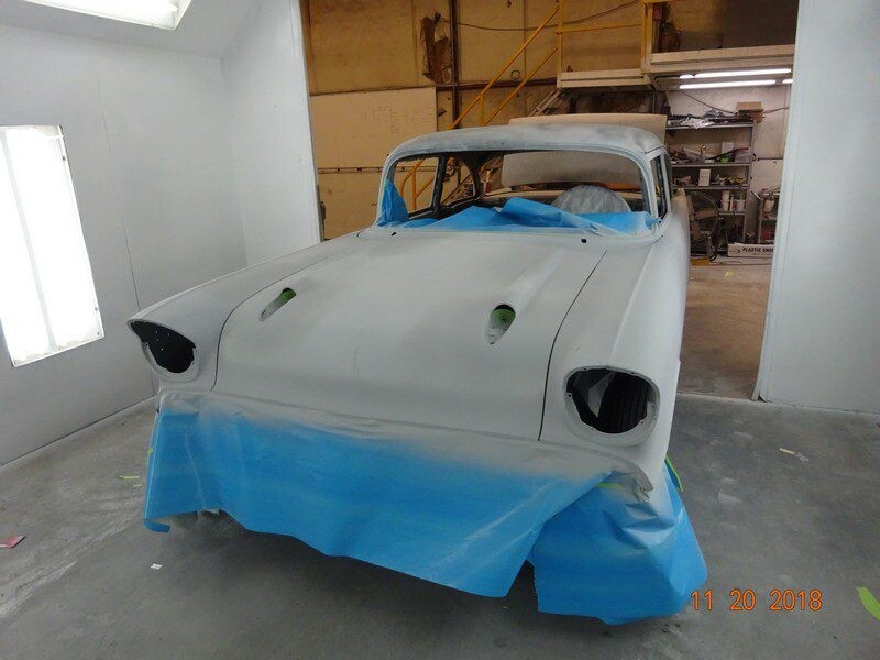 Primered classic car in paint booth.