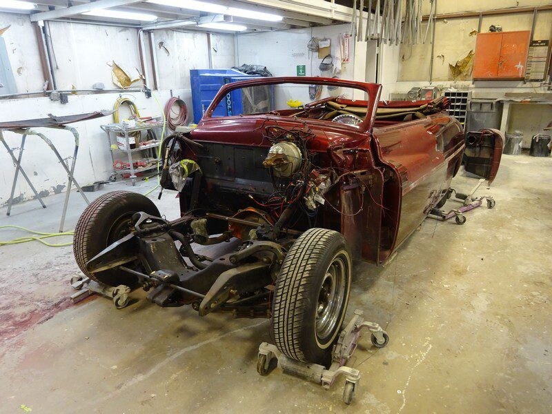 Classic car undergoing restoration in shop.