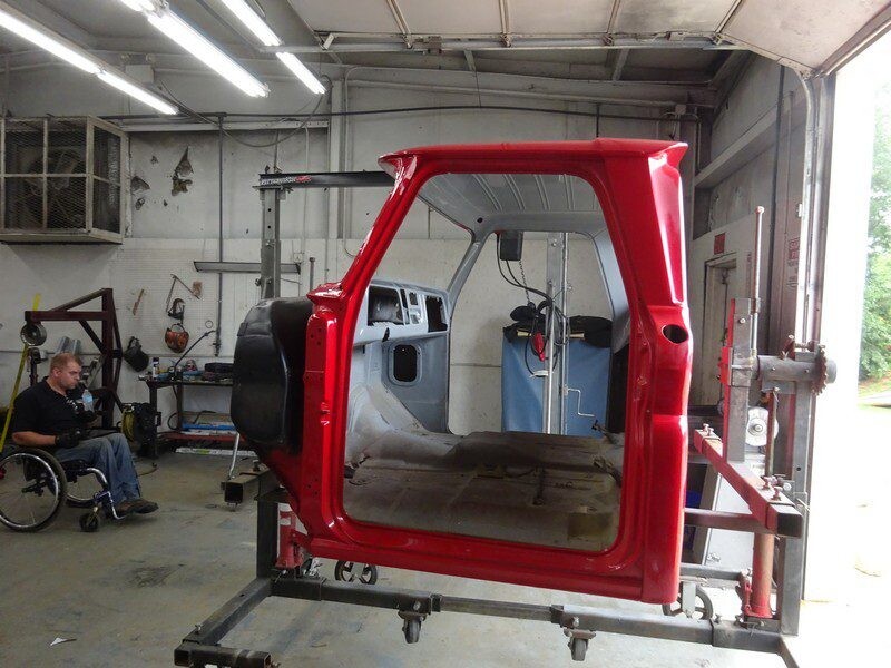 Red truck cab body in auto shop.