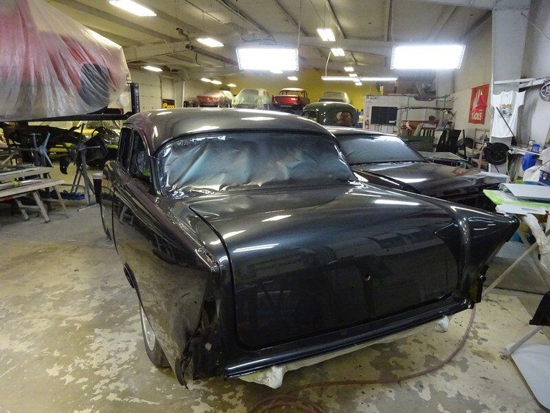 Black classic car in auto body shop.