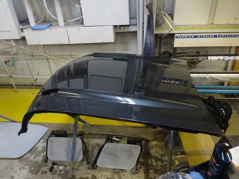 Dark gray car hood on work table.