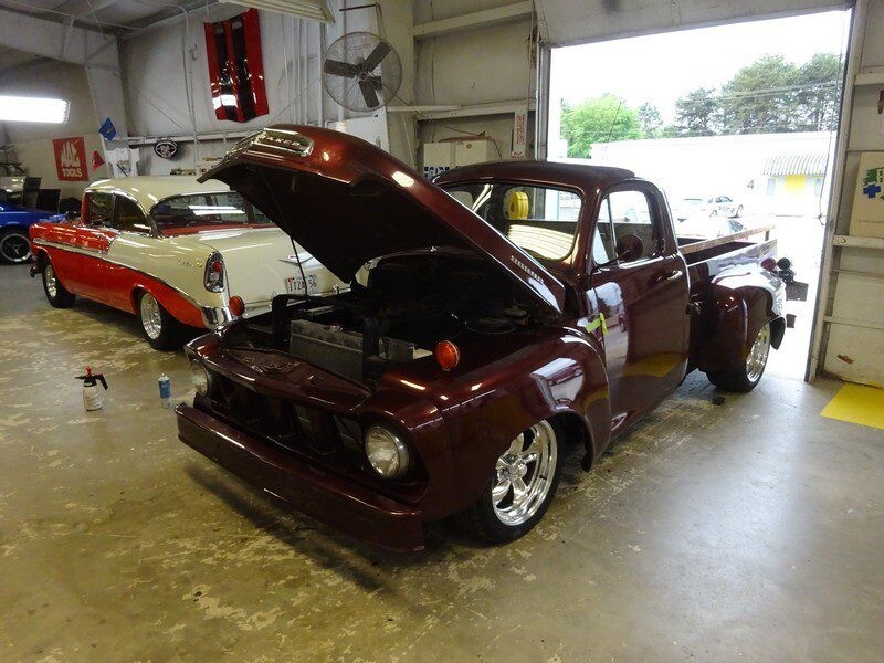 Maroon classic truck and Chevy in garage.
