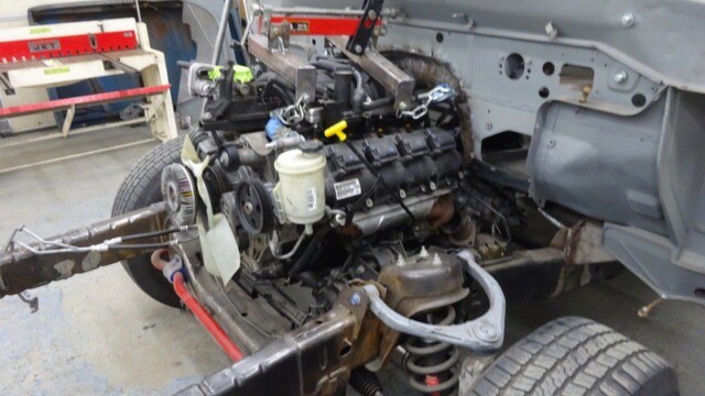 Car engine being installed in chassis.