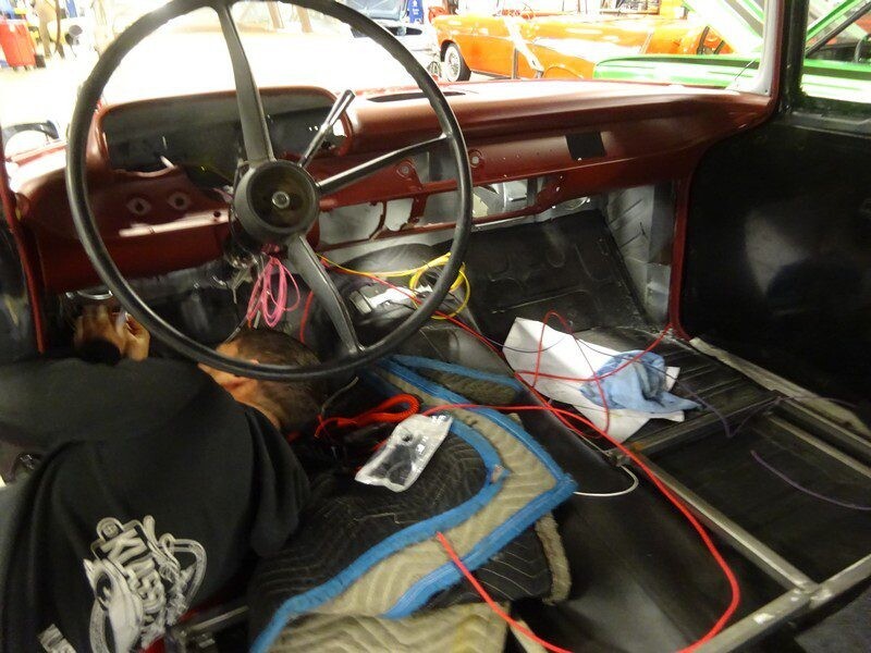 Mechanic working on classic car interior wiring.