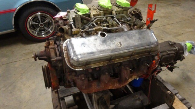 Rusty V8 engine on wooden pallet.
