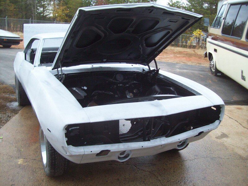 White Camaro under restoration, hood up.