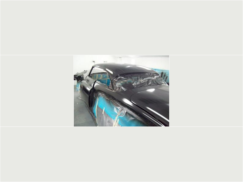 Here's an alt tag for the image: Black classic car in auto body shop.