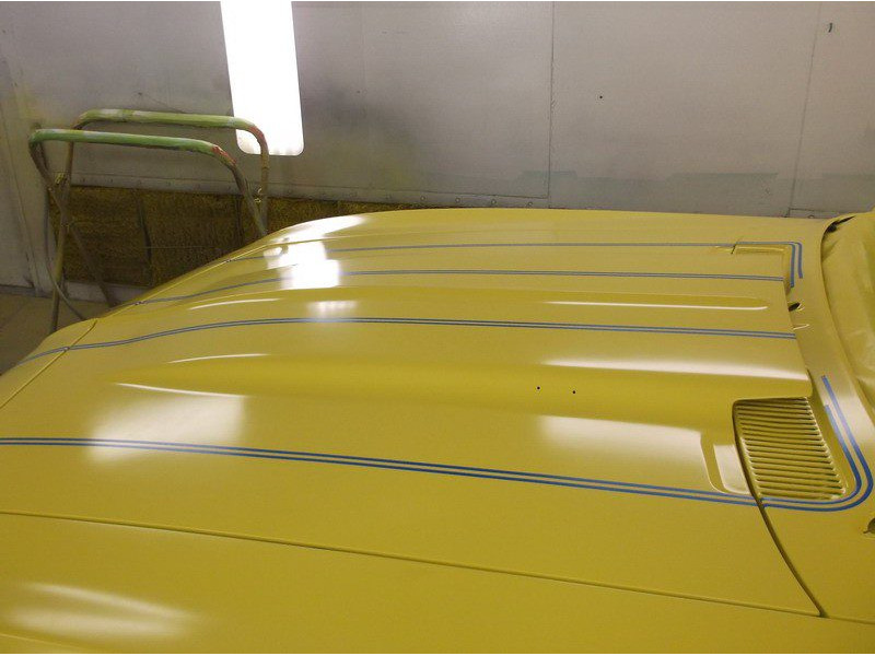 Yellow car hood with racing stripes.