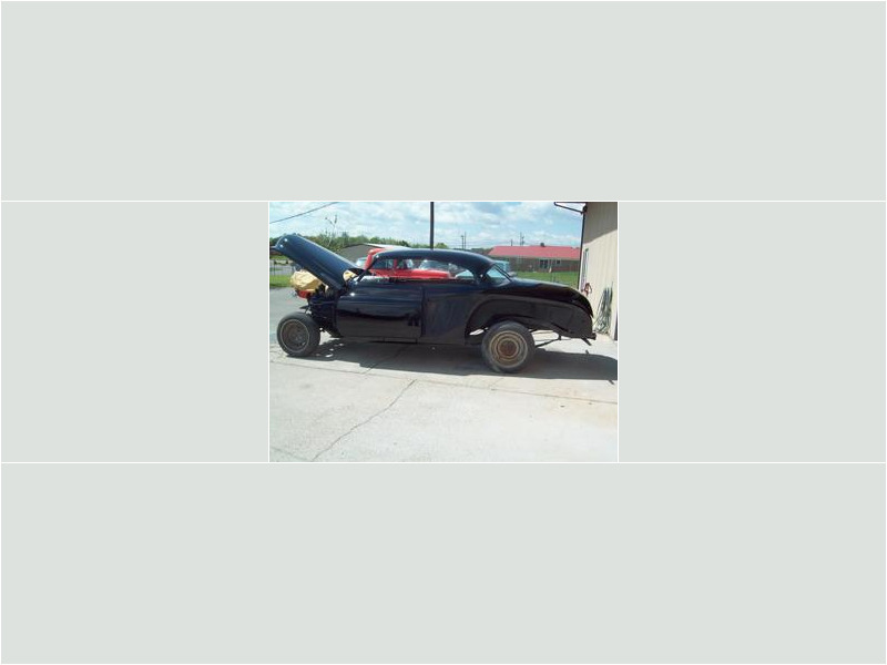 Here's a concise alt tag for the image: Black classic car undergoing restoration.