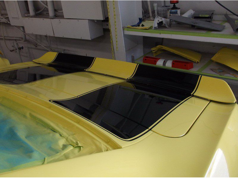 Yellow car with black racing stripes.