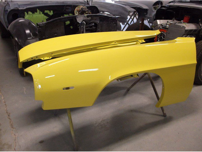 Yellow Camaro body panels in paint shop.