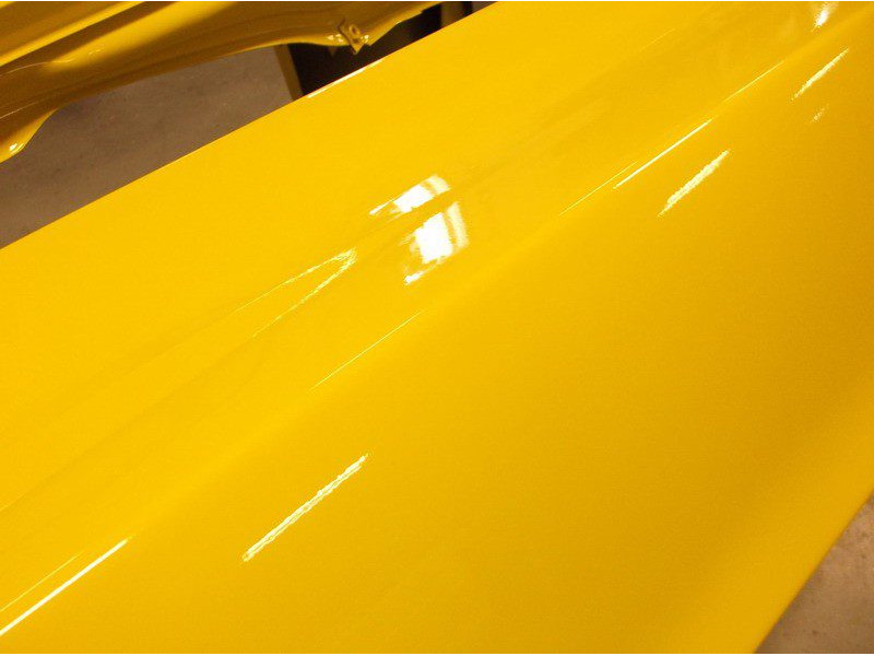 Shiny yellow car part freshly painted.