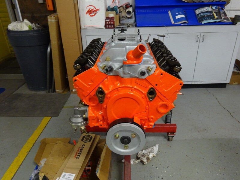 Orange small-block V8 engine on stand.