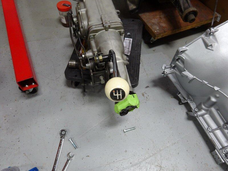 Car transmission parts and tools on floor.