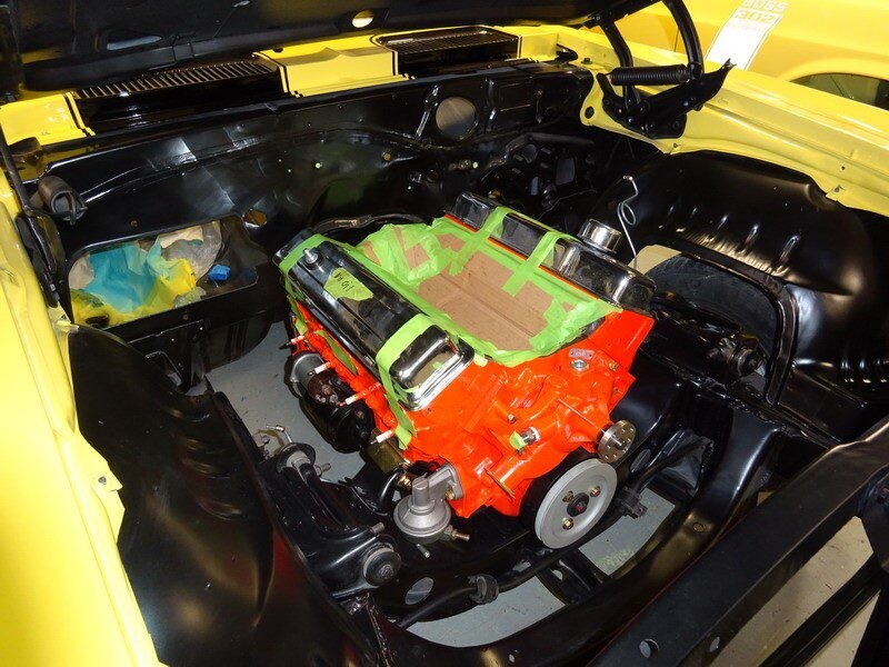 Yellow car engine bay under repair.
