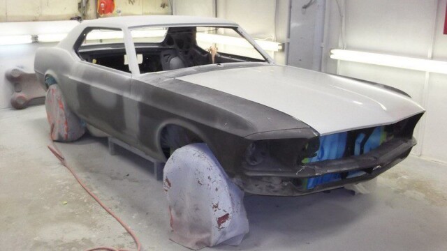 Gray primered Ford Mustang in auto shop.
