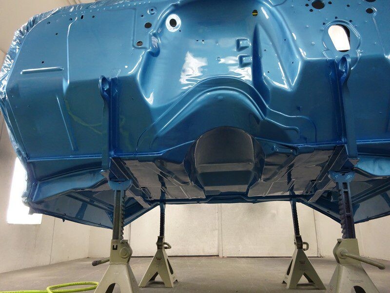 Blue car body underside on stands.