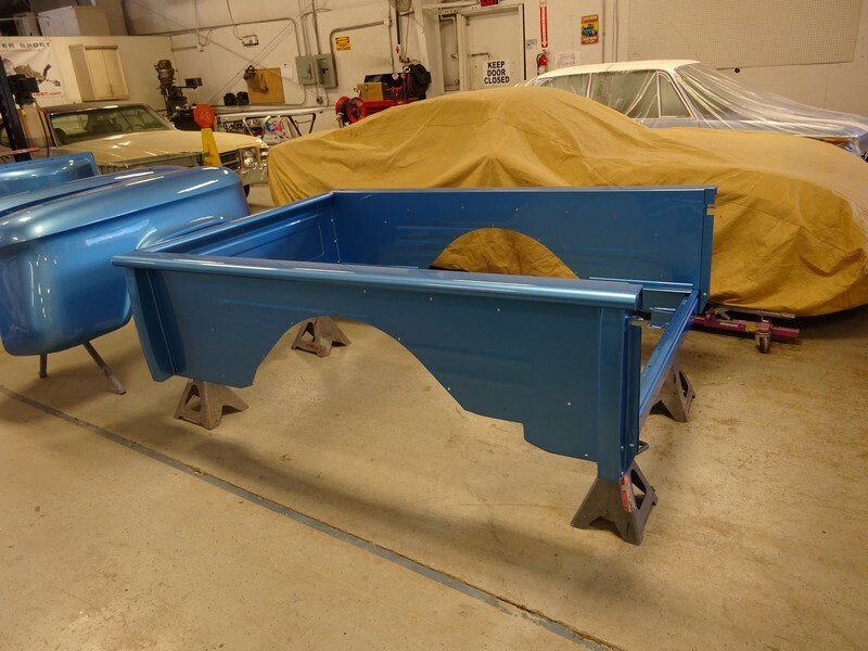 Blue truck bed body panels in shop.
