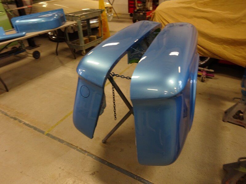 Here's an alt tag for the image: Light blue car body parts drying.