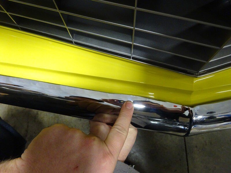 Here's an alt tag for the image: Yellow car's chrome bumper damage.