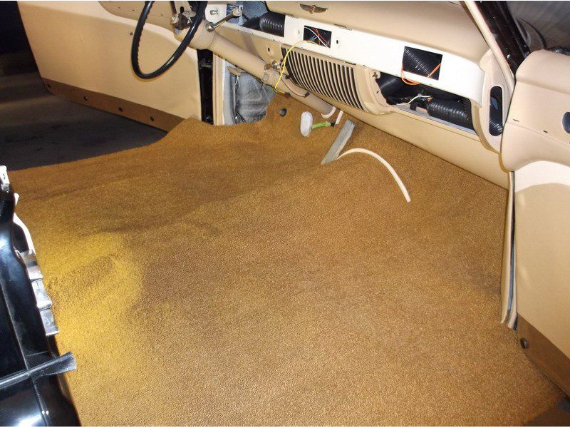 Tan carpeted floor of classic car interior.