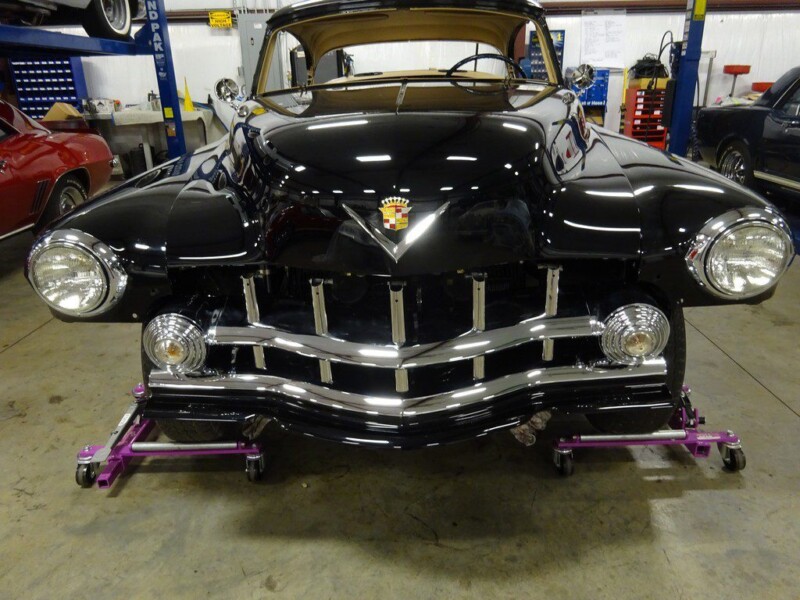 Black classic Cadillac on lift.