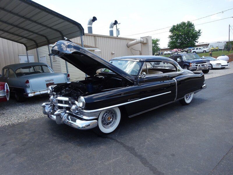 Black classic Cadillac, hood up.