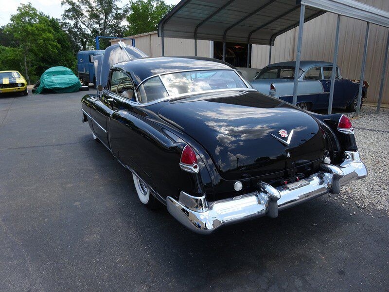 Black classic Cadillac coupe under shelter.