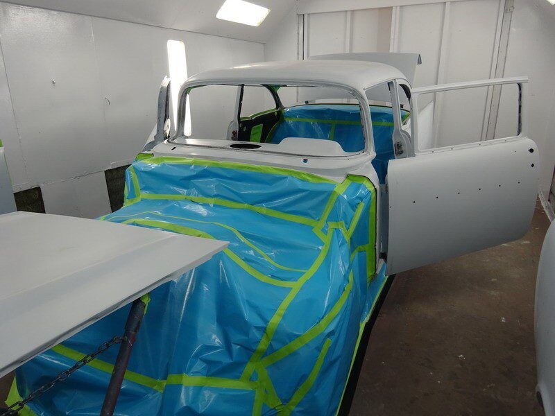 Classic car in paint booth, masked.