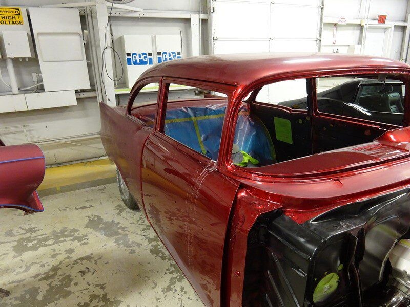 Red classic car in auto body shop.