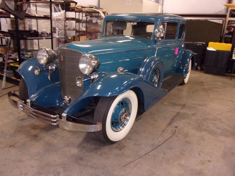 Vintage teal Cadillac coupe in garage.