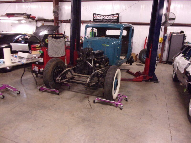 Classic car chassis on lift in garage.