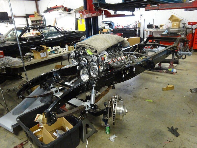 Car chassis under construction in garage.