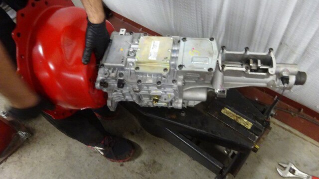 Mechanic holding car transmission.