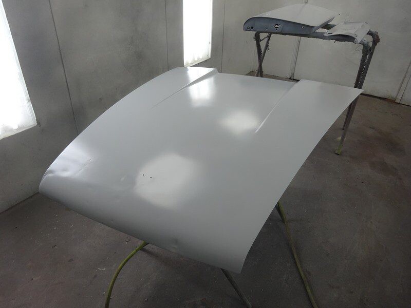 Here's an 8-word alt tag for the image: Grey car hood freshly painted in the shop.