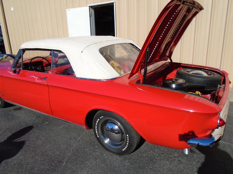 Red classic Corvair convertible, trunk open.