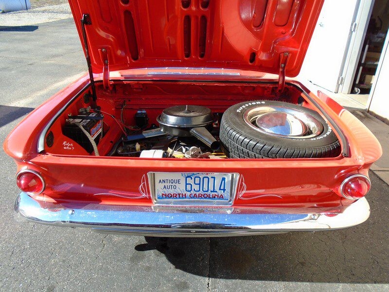 Red classic car trunk open, spare tire.