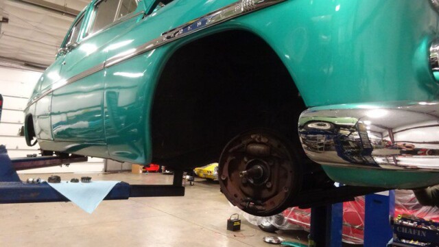Teal classic car on lift, brake repair.