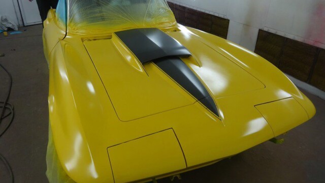 Yellow classic car in paint booth.