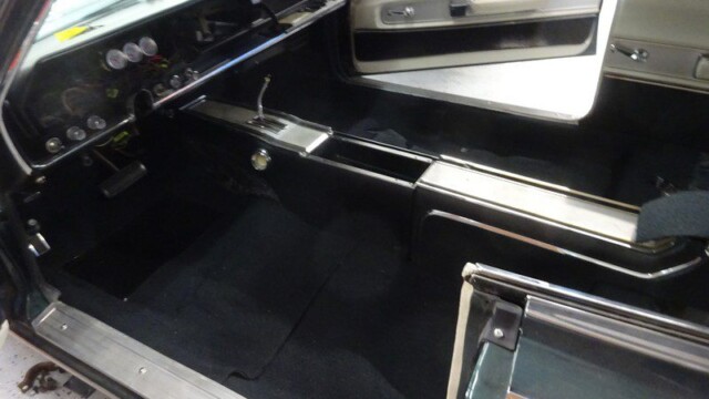 Classic car's interior, black carpet, and gauges.